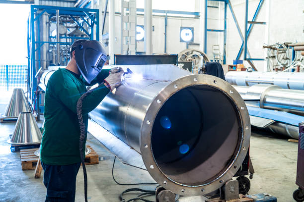 Welder welding stainless steel big pipe at industry workshop