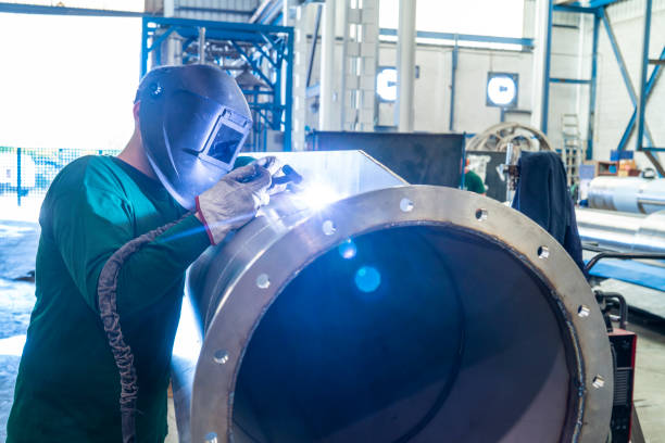 Welder welding stainless steel big pipe at industry workshop